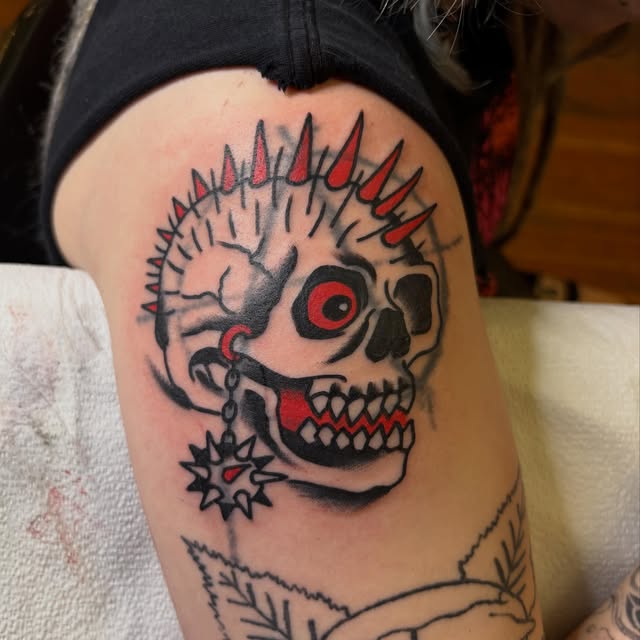 Traditional punk skull tattoo with red spikes and a flail earring