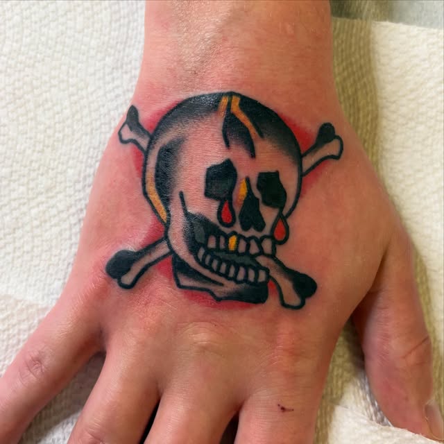 Traditional skull and crossbones tattoo on a hand